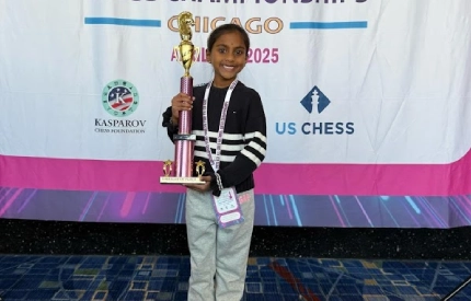 A young student holding a trophy at a US Chess tournament